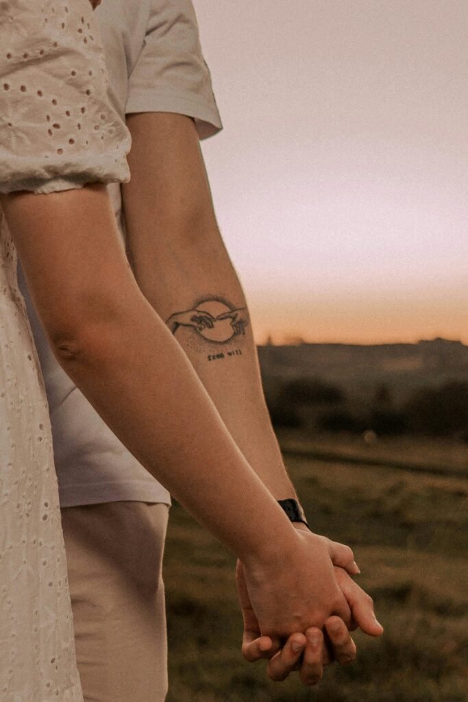 A close-up of a couple holding hands with a scenic sunset in the background.